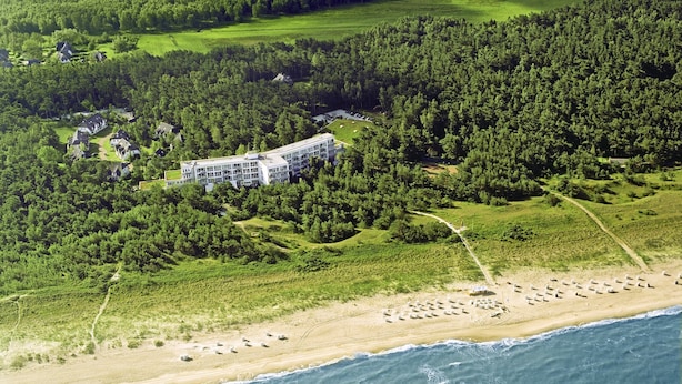 An aerial view of a coastal property with a large building surrounded by dense forest, a sandy beach, and a view of the ocean. - Ferienwohnung fur Zwei Personen, Dierhagen (Ostseebad Dierhagen)