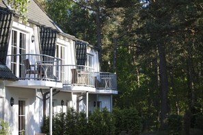 A two-story building with balconies, surrounded by dense trees. - Ferienwohnung fur Zwei Personen, Dierhagen (Ostseebad Dierhagen)