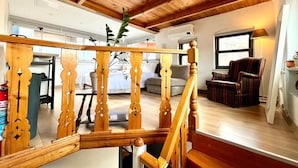 A wooden staircase with a railing, a living room with a sofa and armchair, and a window with a view of the outside. -  The Wooden 17 (Istanbul)