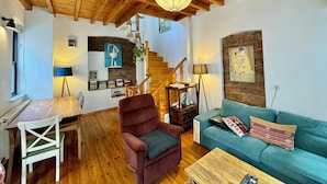 A cozy living room with a wooden ceiling, a staircase, a blue sofa, a red armchair, and a wooden coffee table. -  The Wooden 17 (Istanbul)