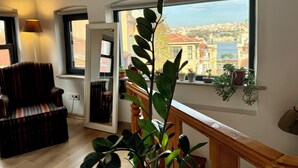 A room with a large window, a striped chair, a potted plant, and a wooden railing. -  The Wooden 17 (Istanbul)