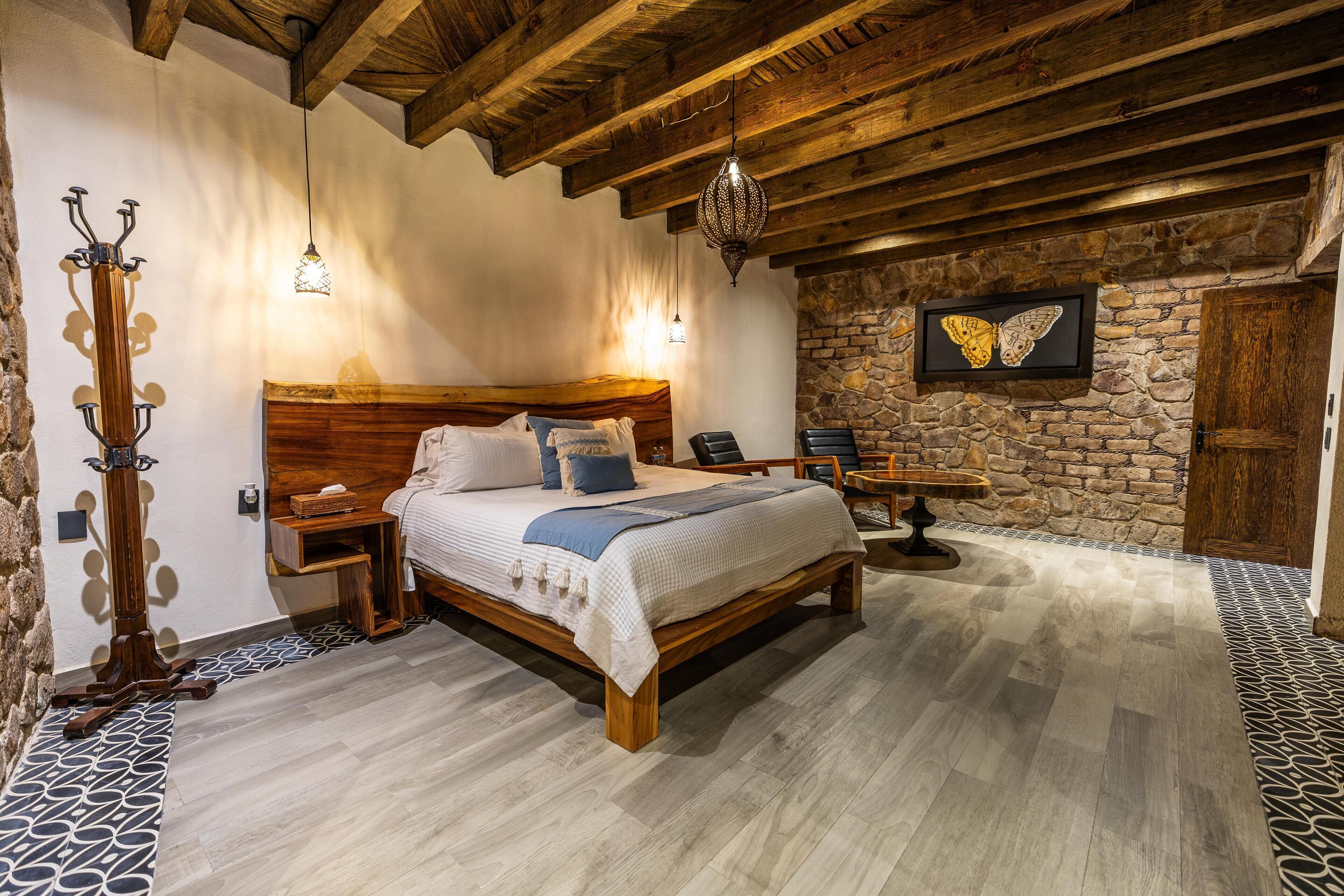 A bedroom with a wooden bed, stone wall, and a butterfly artwork.