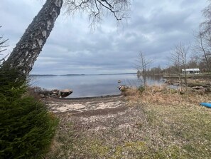 A lakeside view with a dock, trees, and a distant building. - 5 Person Holiday Home in Bredaryd (Bredaryd)