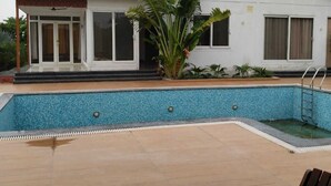 Une maison avec une piscine, une véranda et une grande plante.