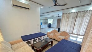 Un salon comprenant un canapé, deux fauteuils, une table basse et un téléviseur.