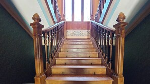 Una escalera de madera con barandilla, que conduce a una plataforma con un muro decorado.