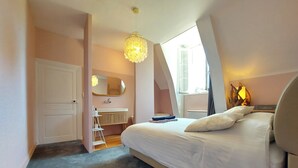 Un dormitorio con cama, mesita de noche, lámpara, espejo, radiador y ventana.