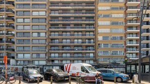 Een meerlaags woongebouw met balkons en een geparkeerde bestelwagen ervoor.