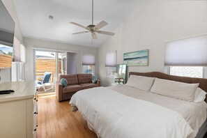 A bedroom with a bed, a ceiling fan, a sofa, and a desk.