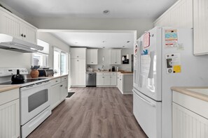 A modern kitchen with white cabinetry, a built-in oven, a dishwasher, and a refrigerator.