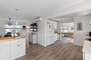 A modern kitchen with white cabinetry, a wooden countertop, and a dining area with a table and chairs.