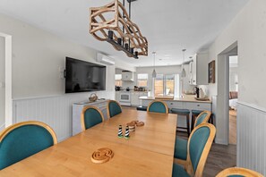 A dining area with a wooden table, teal chairs, and a modern pendant light.