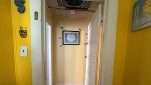 Ein Flur mit gelben Wänden, einem gerahmten Bild an der Wand und einer Tür am Ende.