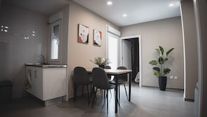 A modern kitchen with a dining area, featuring a sink, cabinets, and a dining table with chairs.