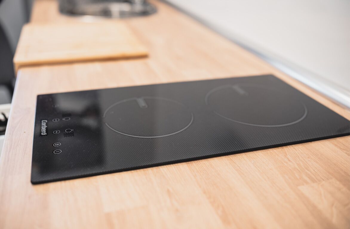 A black induction cooktop on a wooden countertop.