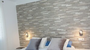 A modern bedroom with a brick-patterned headboard, a neatly made bed with multiple pillows, and bedside lamps.