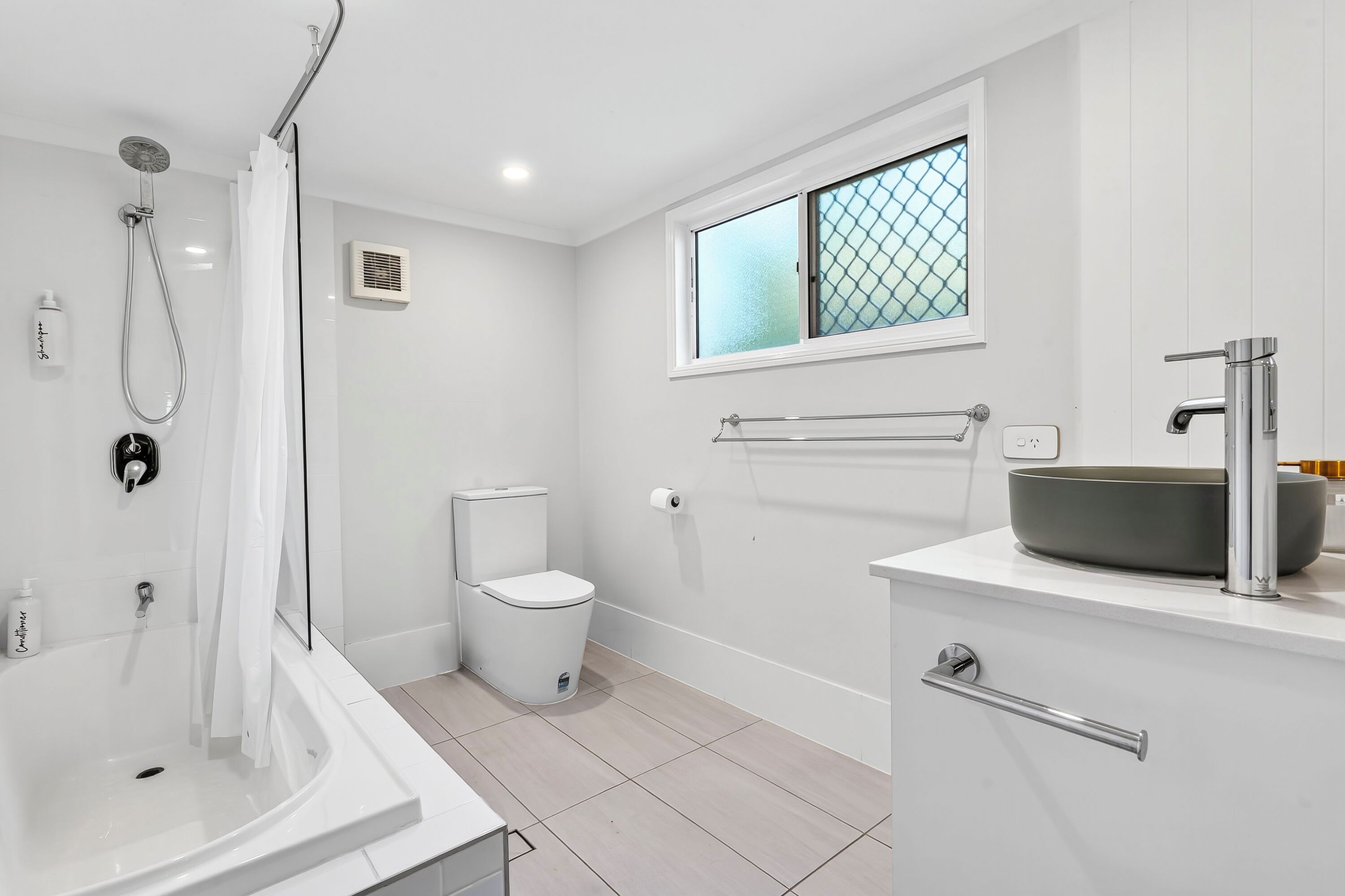 A modern bathroom with a bathtub, toilet, and sink.