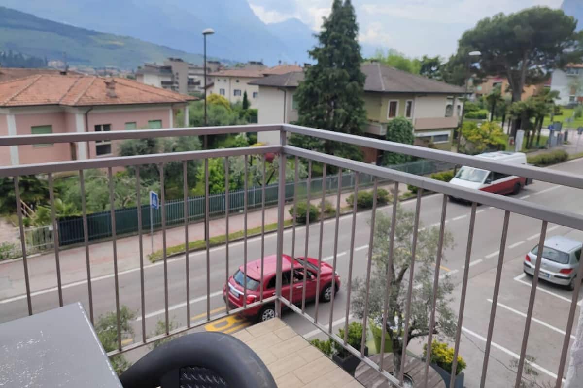 Un balcon donnant sur une rue, des voitures et des maisons.