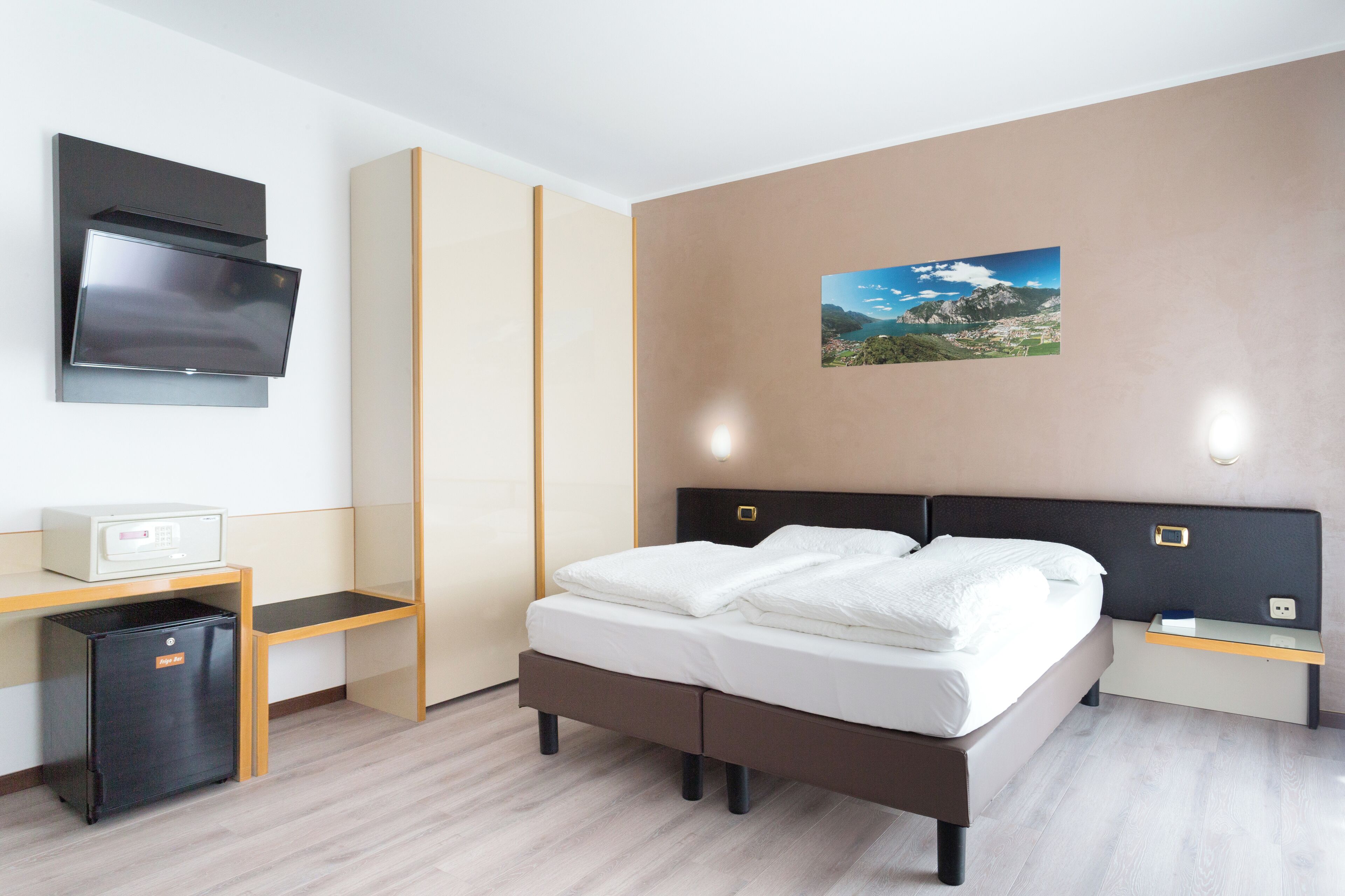 Une chambre d’hôtel moderne équipée d’un lit, d’un bureau, d’une télévision et d’un petit réfrigérateur.