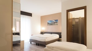 Een hotelkamer met een groot bed, nachtkastje, spiegel, kledingkast en een aan de muur hangend schilderij.