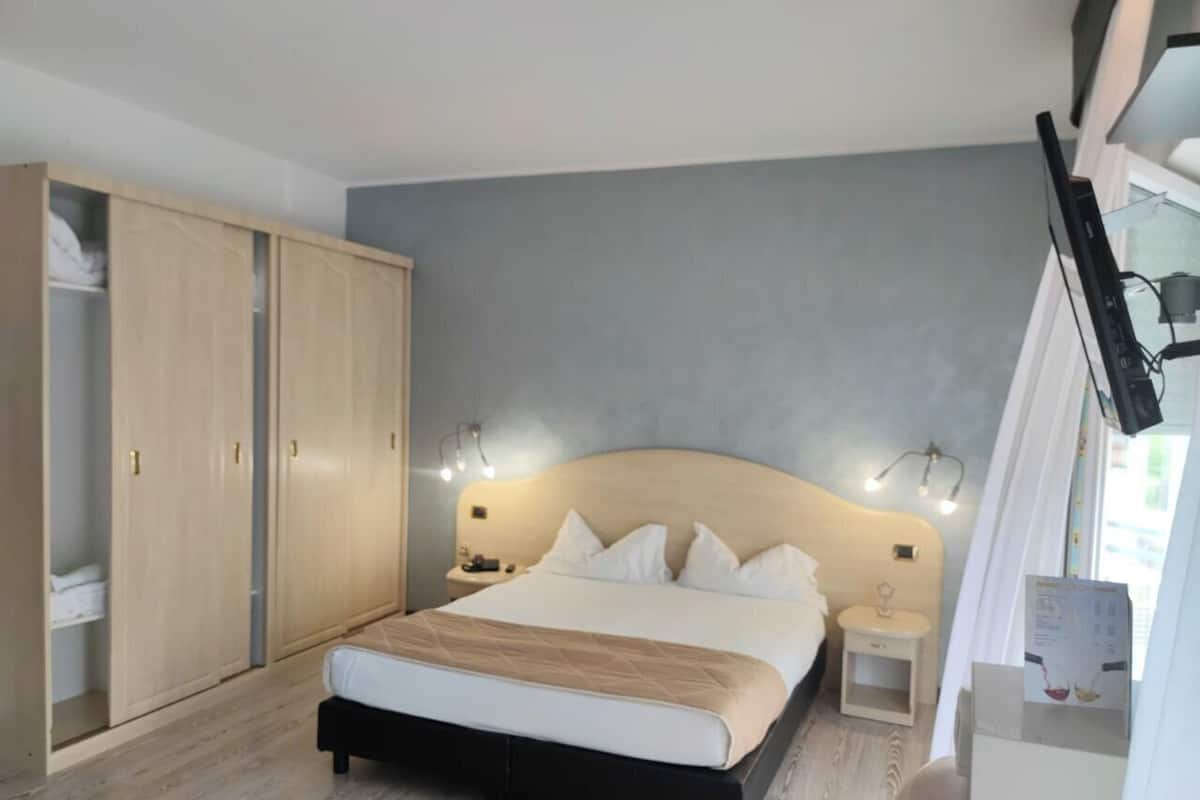 Une chambre à coucher avec un lit, des tables de chevet, une armoire et une fenêtre avec des rideaux.