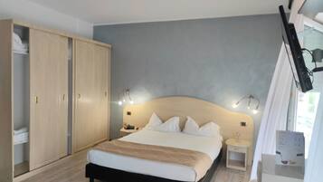 Ein Schlafzimmer mit Bett, Nachttischen, einem Kleiderschrank und einem Fenster mit Vorhängen.
