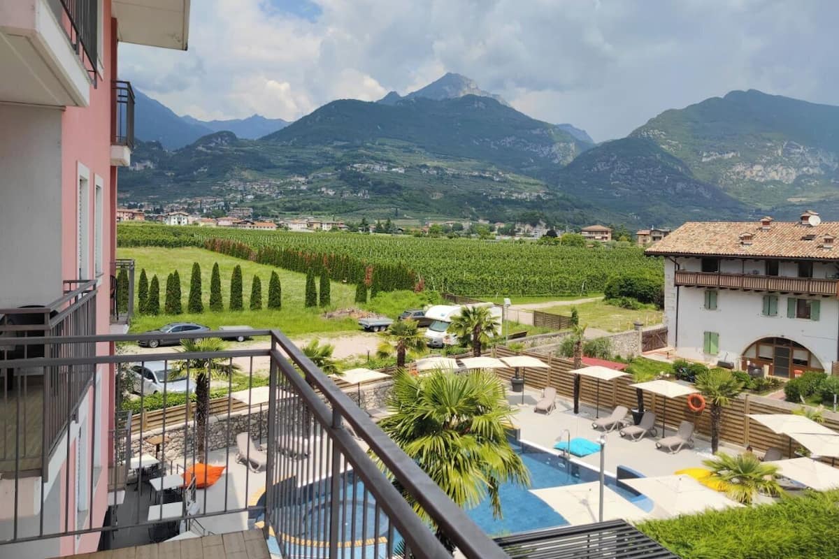 Un balcon avec vue sur une chaîne de montagnes, une piscine et un vignoble.