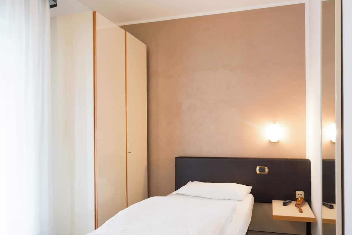 Une chambre d’hôtel comprenant un lit, une table de chevet, un miroir et une armoire.