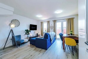 Un salon moderne avec un canapé, une table à manger, un téléviseur et une horloge au mur.