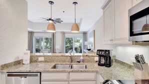 A modern kitchen with granite countertops, stainless steel appliances, and pendant lighting. - Located in the heart of the south end.  Close to everything (Saint Simons Island)