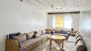 A spacious living room with a large sofa set, a coffee table, and a chandelier. - Family apartment near the sea (Martil)