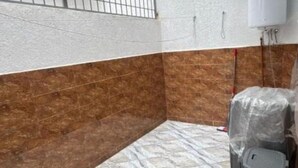 A bathroom with brown and white tiles, a shower area, and a covered trash bin. - Family apartment near the sea (Martil)