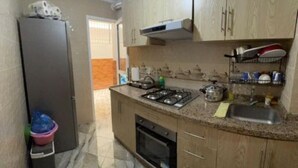 A compact kitchen with a refrigerator, stove, oven, and a sink. - Family apartment near the sea (Martil)