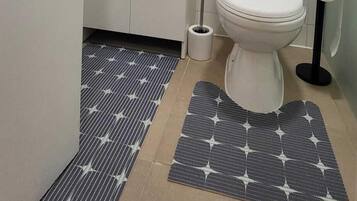Une salle de bain équipée d’un WC, d’un lavabo, d’un miroir et d’un porte-rouleau de papier toilette.