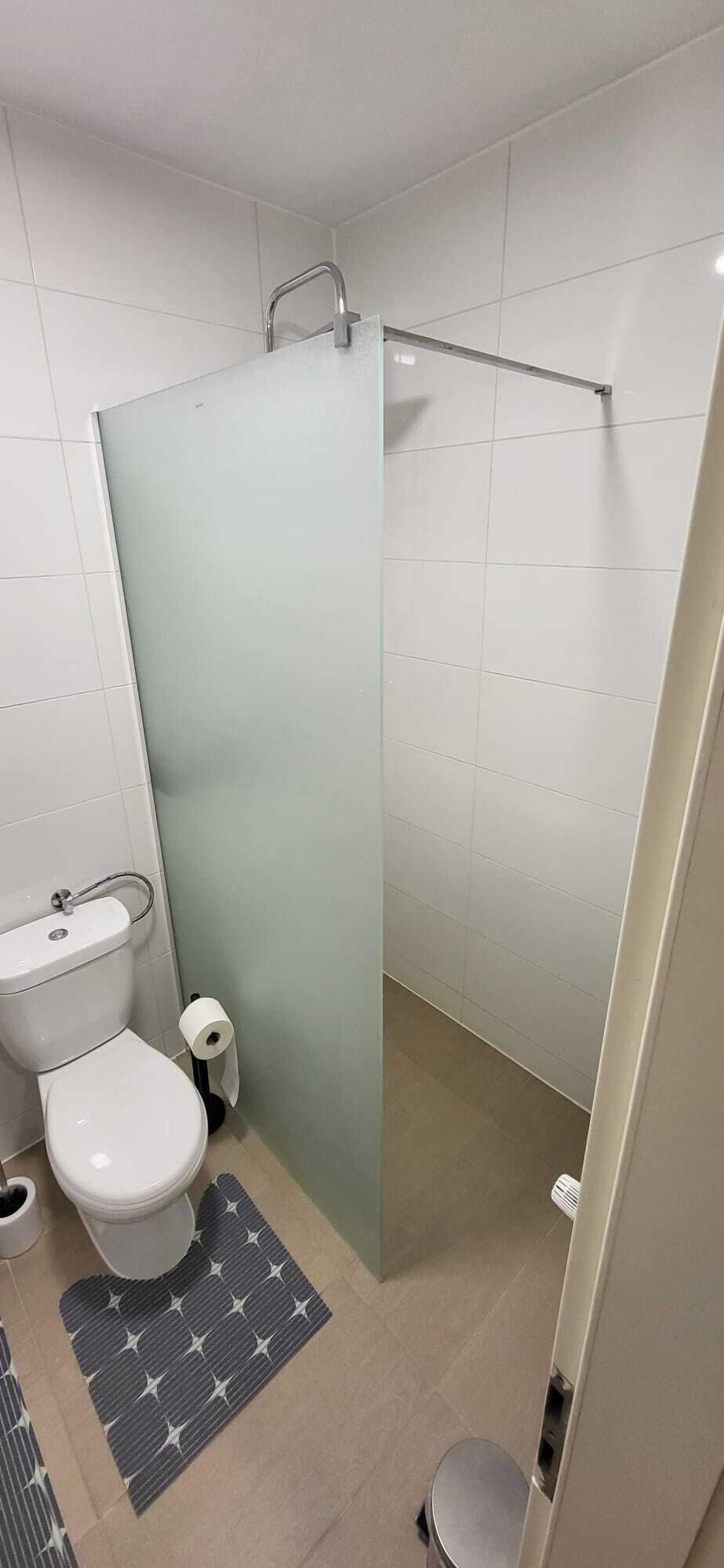 Een moderne badkamer met toilet, bidet en een douchecabine met glazen wanden.