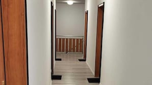 A hallway with wooden flooring and white walls. - Pension Wolf (Hohe Börde)