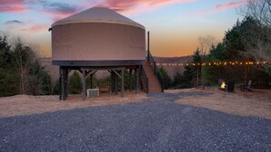 A large, dome-shaped tent with a staircase leading up to it, surrounded by trees and a gravel ground. - Horizon Hideout | Hot Tub, Mountain Views, Nature Escape (Reynoldsville)