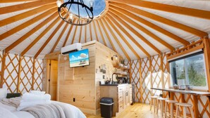 A yurt with a bed, kitchenette, and a TV. - Horizon Hideout | Hot Tub, Mountain Views, Nature Escape (Reynoldsville)