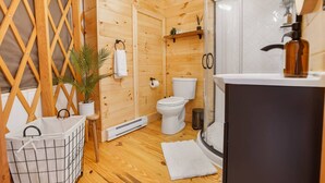 A wooden cabin bathroom with a toilet, shower, and sink. - Horizon Hideout | Hot Tub, Mountain Views, Nature Escape (Reynoldsville)