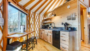A compact kitchen with wooden cabinets, a sink, and a window overlooking a snowy landscape. - Adventure Abode | Modern Yurt w/ Hot Tub, Bubble Dome + ADA Access (Reynoldsville)
