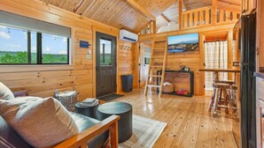 Ein gemütliches Blockhaus-Interieur mit Holzwänden, einer Couch, einem Esstisch und einer Küchenzeile.