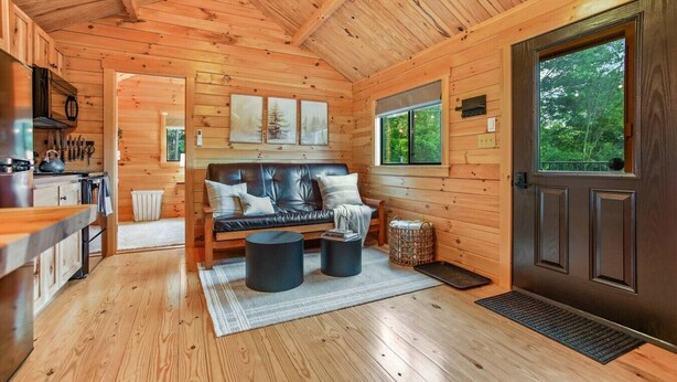 Ein gemütliches Blockhaus-Interieur mit Holzausstattung, einer Couch, einem Esstisch und einer Küchenzeile.