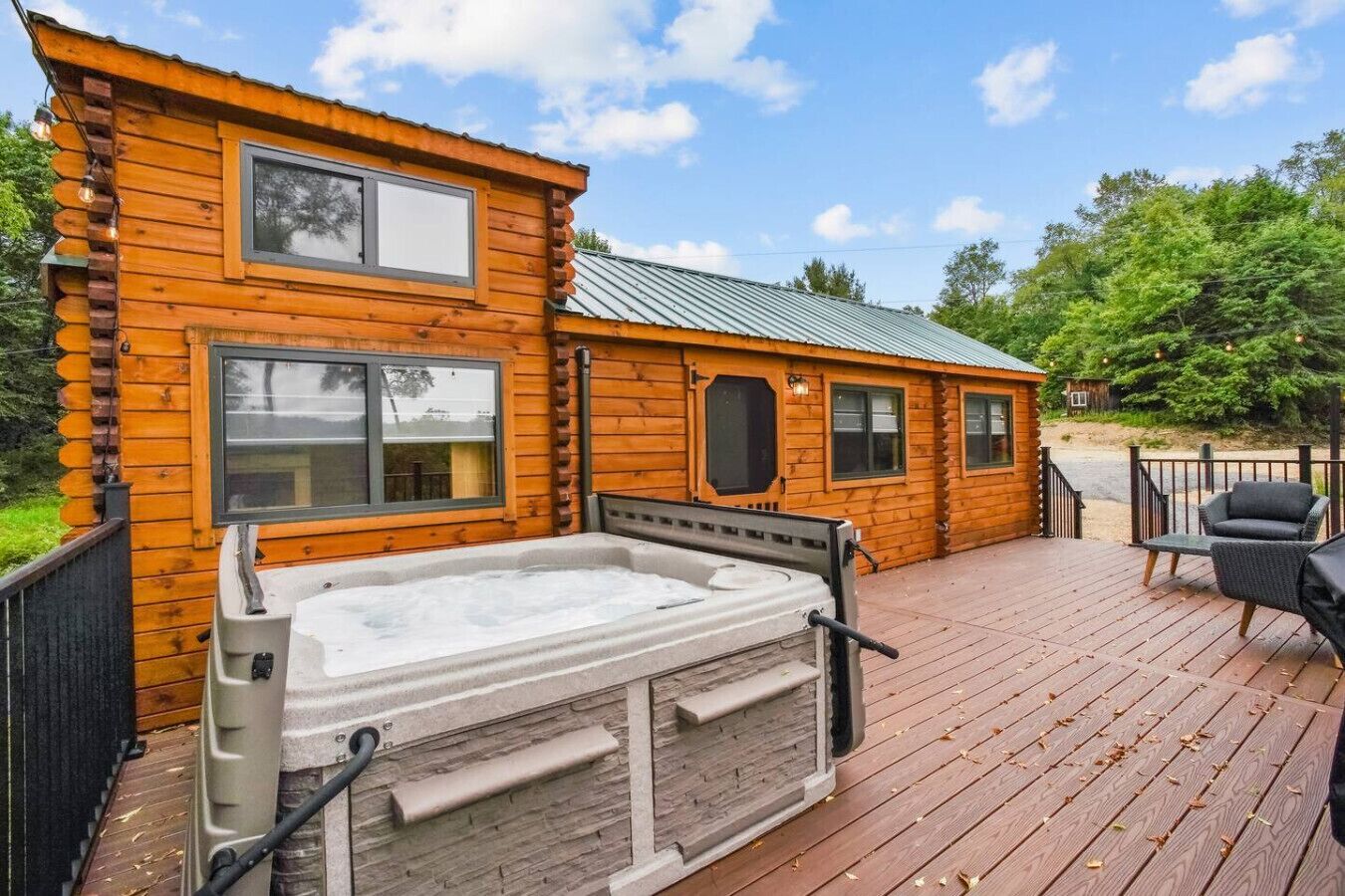 Una cabaña de troncos con jacuzzi, terraza y mobiliario exterior.