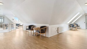 A spacious attic room with wooden flooring, two black leather chairs, and a white ceiling with skylights. - 4 Star Holiday Home in Harboore (Harboore)