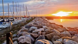 A marina with boats docked along a rocky shoreline during sunset. - 6 Person Holiday Home in Dronningmolle (Dronningmolle)