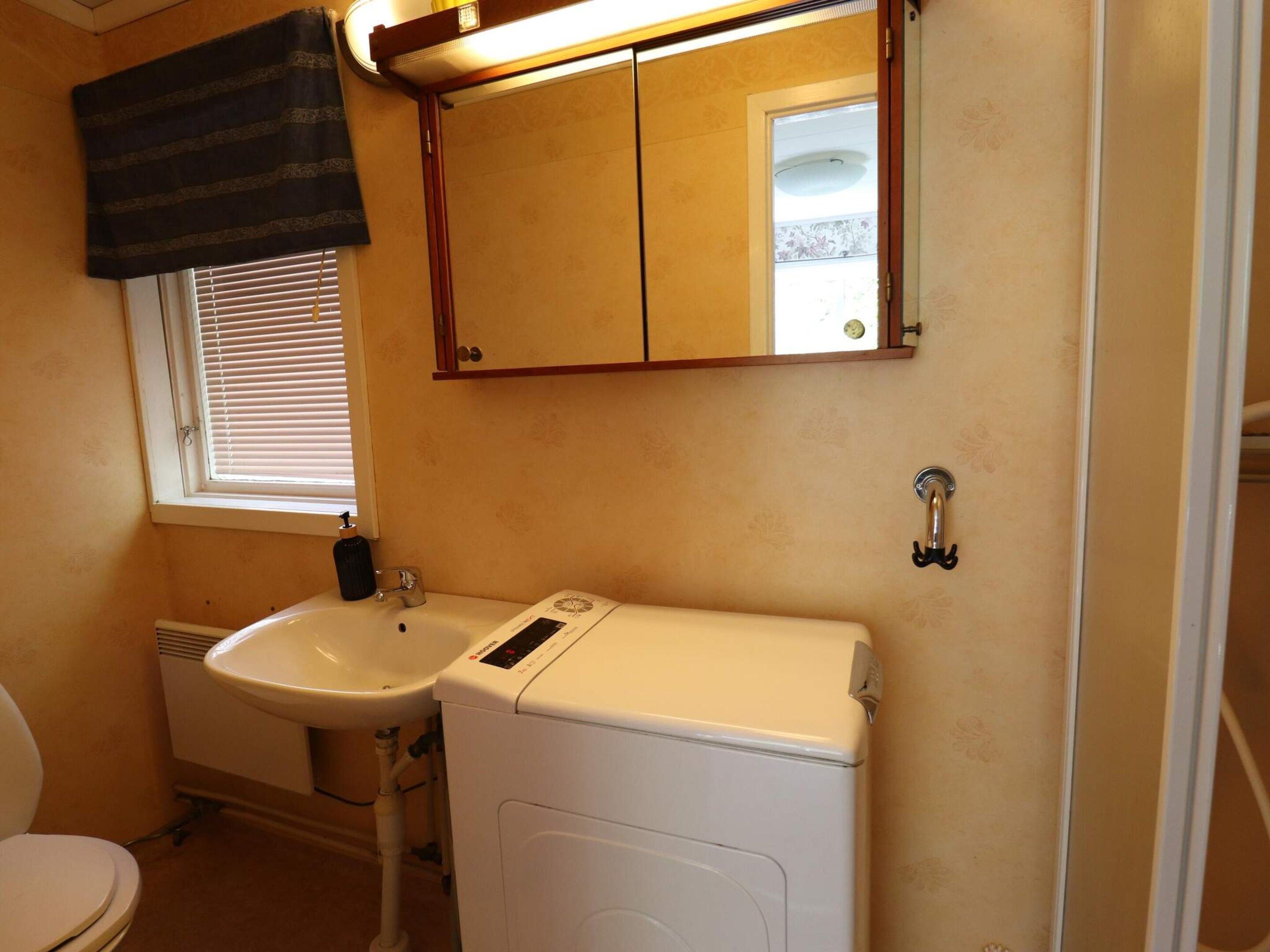 A bathroom with a toilet, sink, and washing machine.