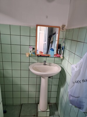 A bathroom with a pedestal sink, a mirror, and green tiled walls. - 2 bedroom apartments, fully equipped kitchen at kwatta with security (Paramaribo)