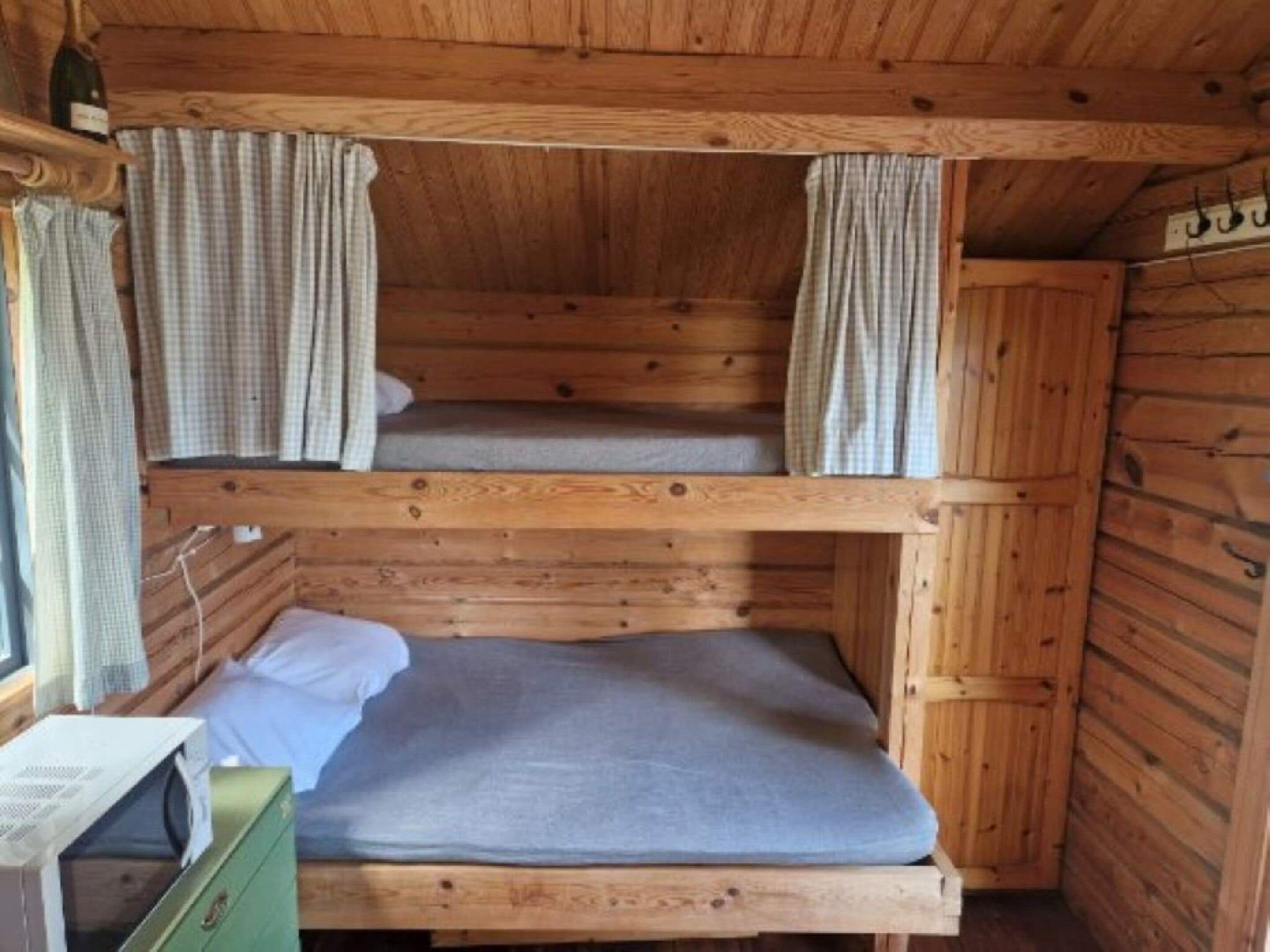 A bunk bed room with wooden walls and curtains.