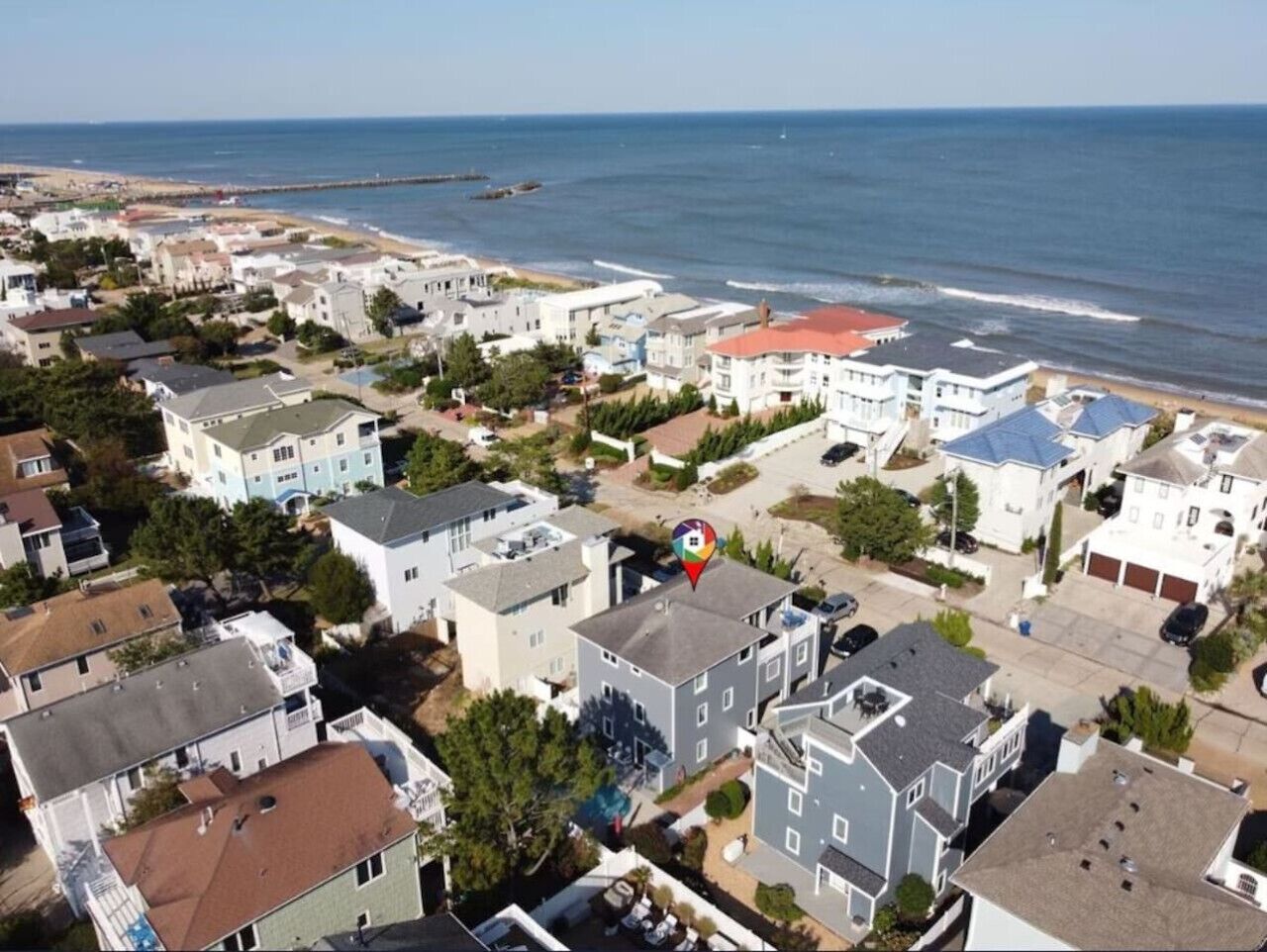 A coastal residential area with houses, a beach, and a pier.