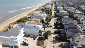 Zona residencial costera con casas a lo largo de la playa, con una mezcla de edificios de uno y varios pisos, algunos con balcones a la vista.